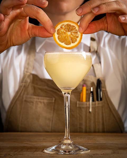 Bartender setting a lemon on a drink at Covina.