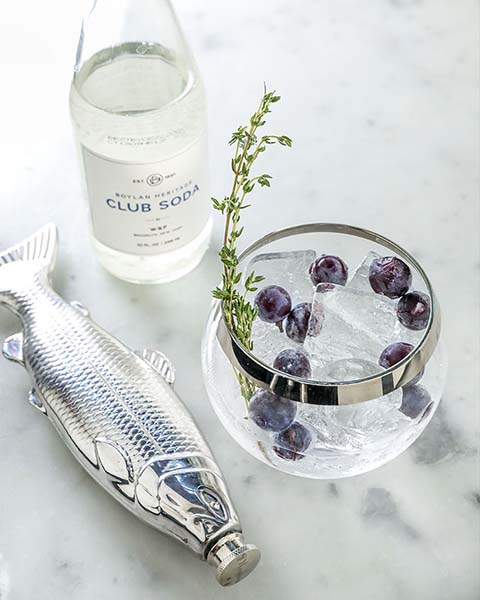 Cocktail served with blueberries and a fish flask at the restaurant Shuka.