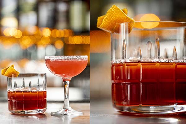 Two cocktails sittting on top of a bar. 