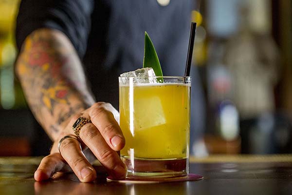 A tatooed bartender serving a cocktail at Salvation Taco in NYC.