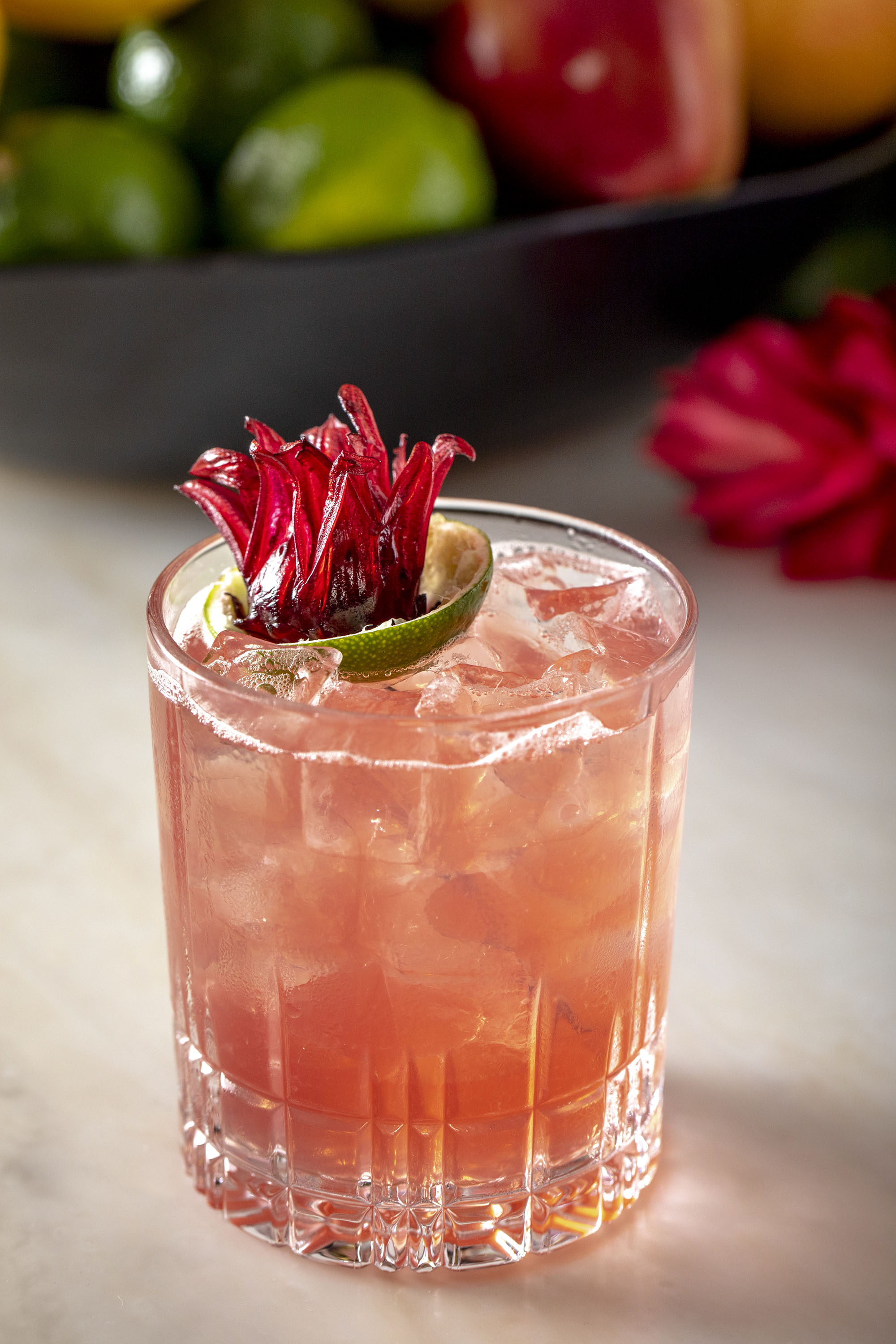 A cocktail with a lime and flower garnish.