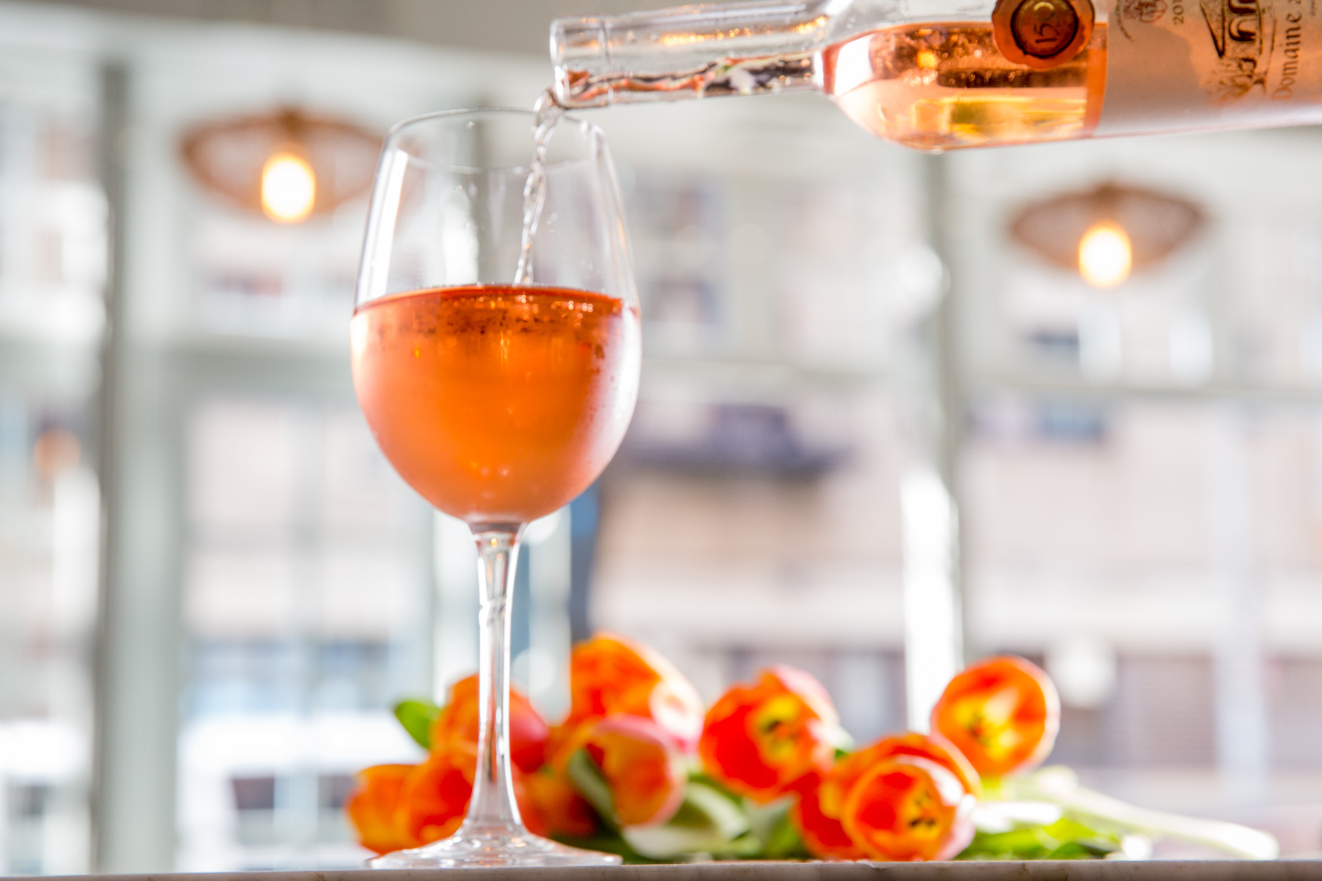 Flowers next to a glass of wine being poured